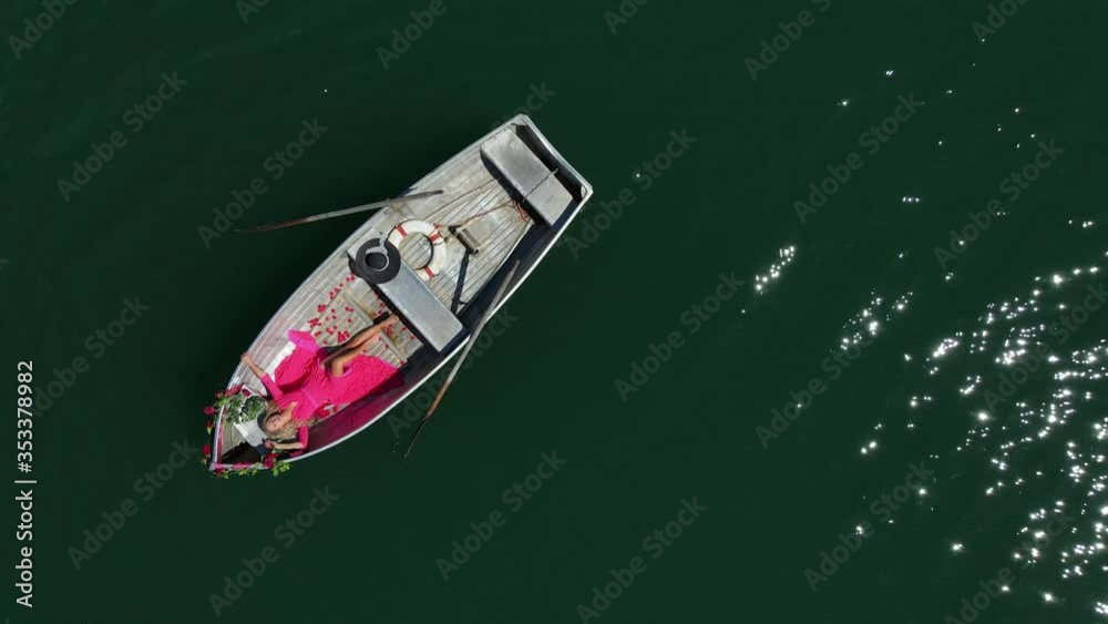 Pretty woman in red dress with long blond hair, relaxing in a boat on a mountain lake in Switzerland Pretty woman in red dress with long blond hair, relaxing in a boat on a mountain lake in Switzerland