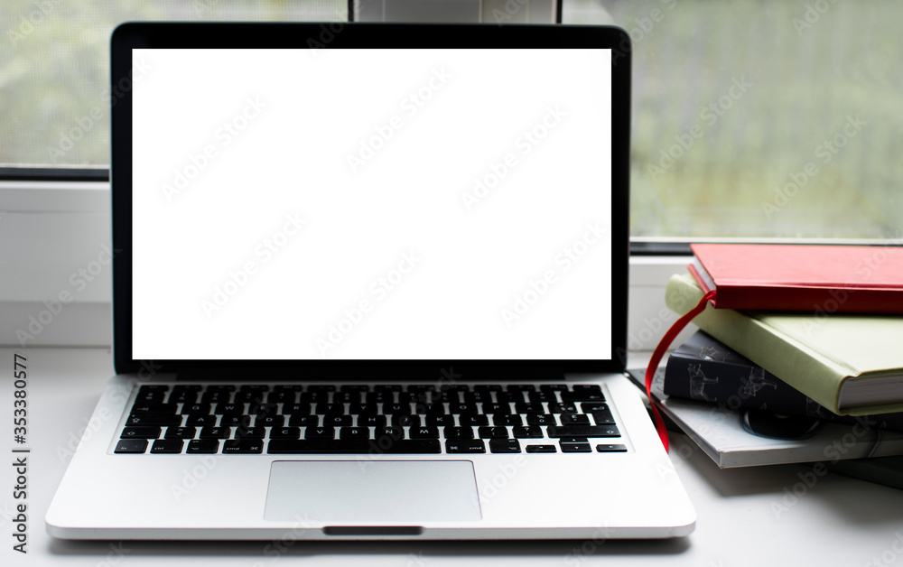 laptop with white screen for text on the window with phone and books laptop with white screen for text on the window with phone and books