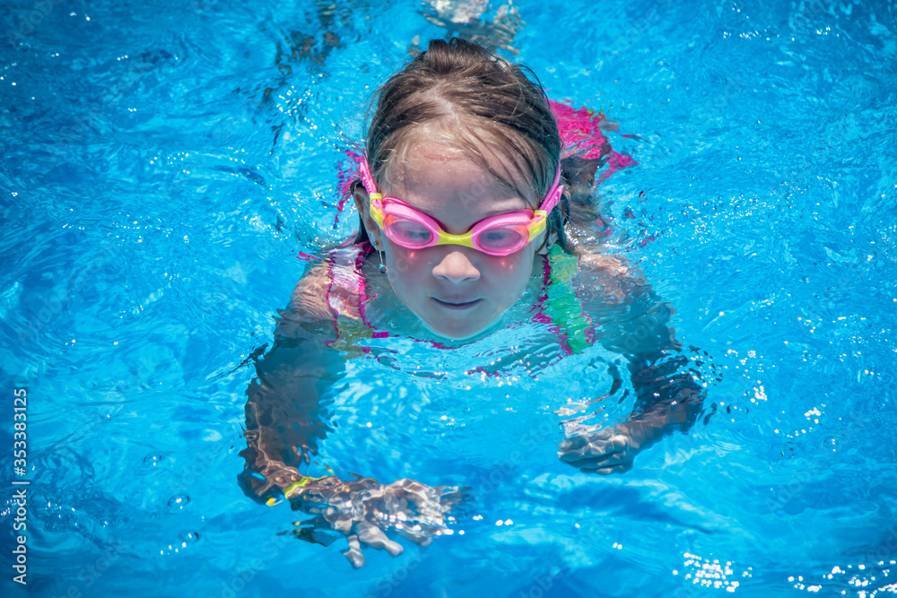 Summer vacation, healthy lifestyle and happy childhood concept. Close up portrait of young child girl swimming in pool.