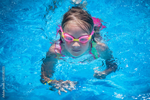 Summer vacation, healthy lifestyle and happy childhood concept. Close up portrait of young child girl swimming in pool.