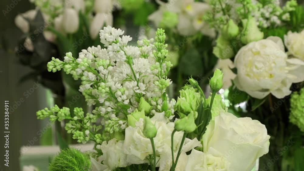 White lilac and white roses with green leaves on the festive table close up White lilac and white roses with green leaves on the festive table close up