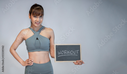 Young Asian woman holding workout label in gym.Weight loss concept. photo