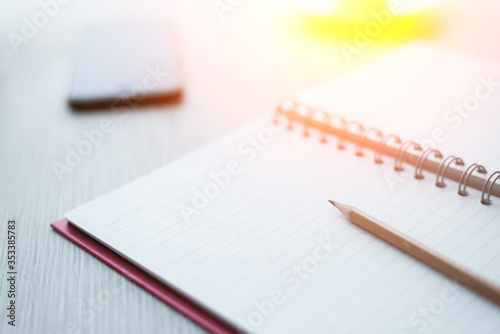 Top view of Notebook with pencil , and cup of coffee on white wooden table.