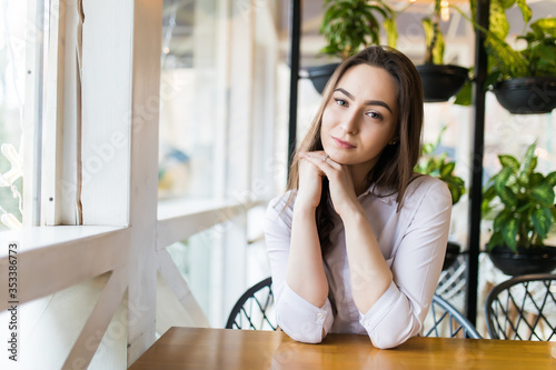 Happy woman sitting and waiting for order in cafe