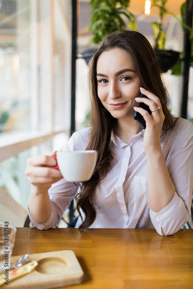Attractive woman with cute smile having talking conversation with mobile phone while rest in cafe Attractive woman with cute smile having talking conversation with mobile phone while rest in cafe