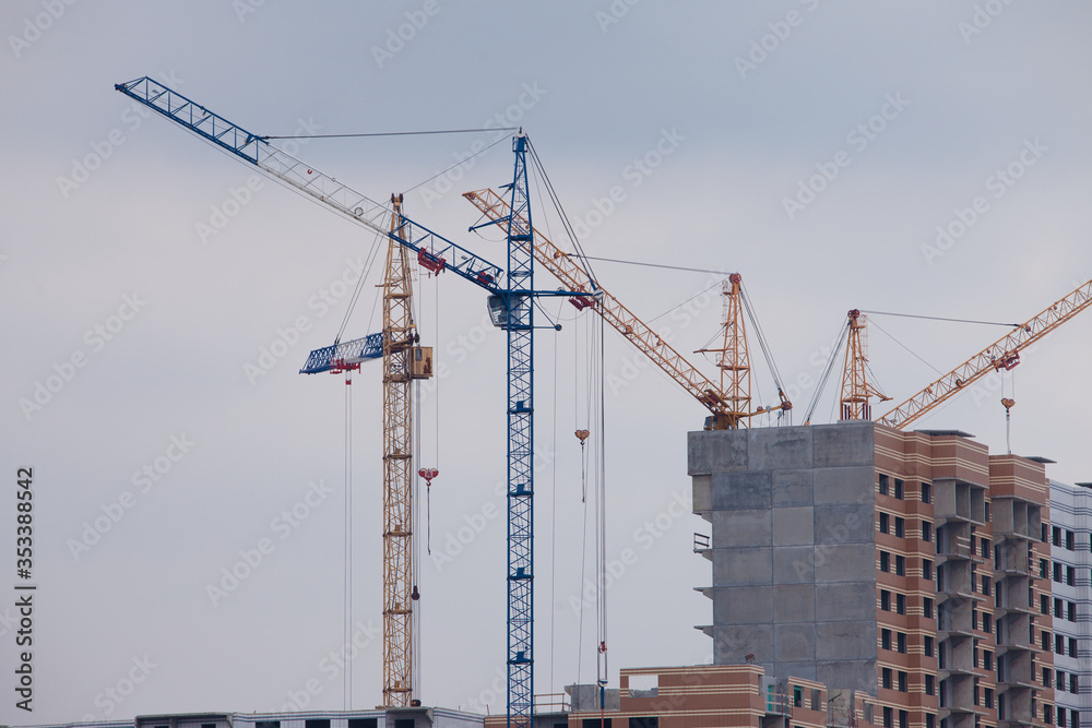 Photo of a residential building under construction on a gray day with construction cranes