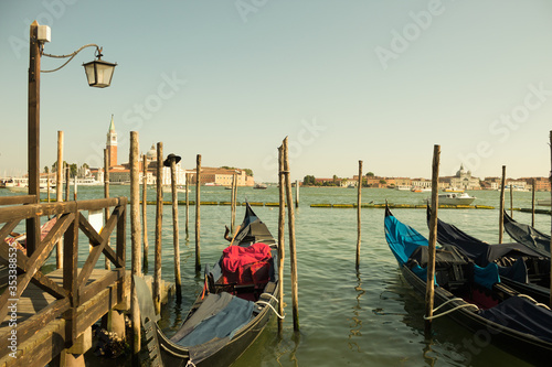 Gondolas moored on the pier of Saint Mark square (Piazza San Marco), in the background is San Giorgio di Maggiore church, Venice, Italy © julianjuly