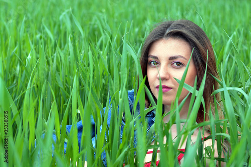 Girl with beautiful hair lying in the green, juicy grass. Warm spring evening