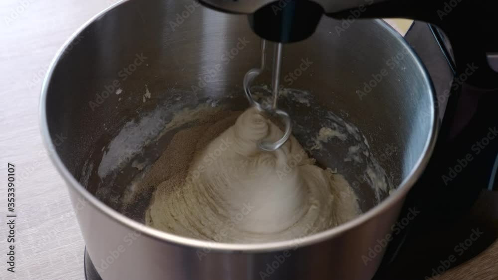 detail of man's hands pouring yeast on a dough inside a working bread kneader detail of man's hands pouring yeast on a dough inside a working bread kneader