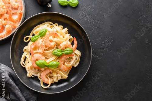 Italian pasta fettuccine with prawn, shrimps in bowl on black table. Space for text.