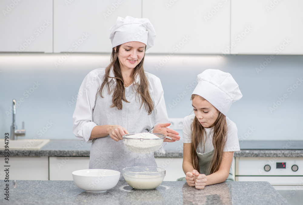 Happy family at home. Mom and her young daughter cook in the kitchen Happy family at home. Mom and her young daughter cook in the kitchen