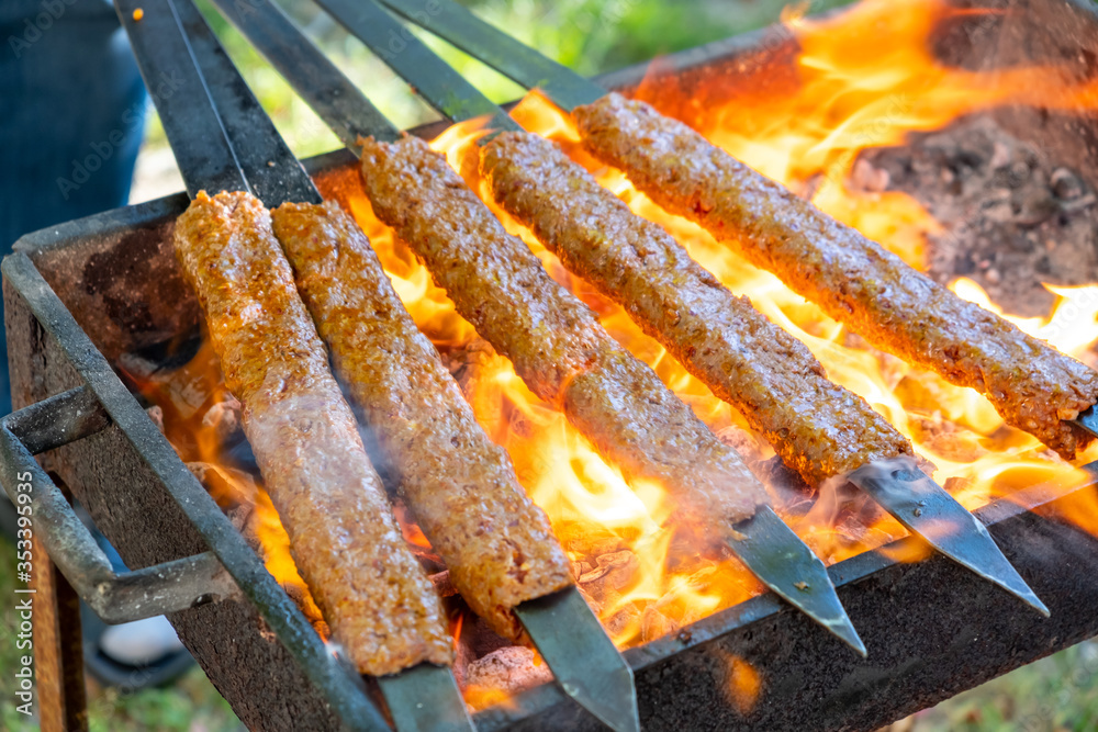 Traditional Turkish Adana Kebap on the grill with skewers for dinner.  Turkish cuisine food culture in Turkey. Adana kebab on the mangal in  nature. Picnic. Stock Photo | Adobe Stock