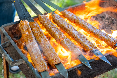 Traditional Turkish Adana  Kebap on the grill with skewers  for dinner. Turkish cuisine food culture in Turkey. Adana kebab on the mangal in nature. Picnic.