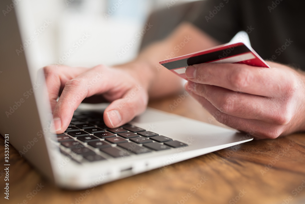 online shopping concept, person entering payment information on laptop computer holding debit or credit card in other hand online shopping concept, person entering payment information on laptop computer holding debit or credit card in other hand
