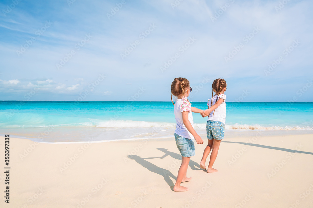 Adorable little girls have a lot of fun on the beach.