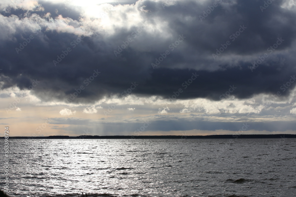 Beautiful silvery morning.Voluminous lush gray clouds over the steel shimmering water of the lake at dawn.Russia