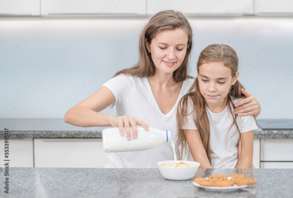 Happy family at kitchen. Mom and her young daughter have breakfast at home. Empty space for text