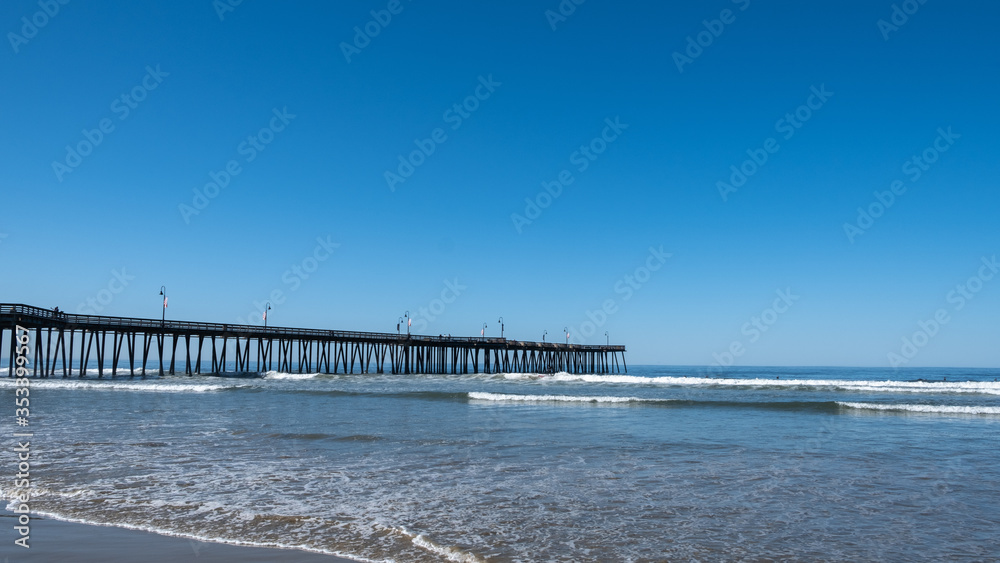 pier, beach, waves, sand and people strolling