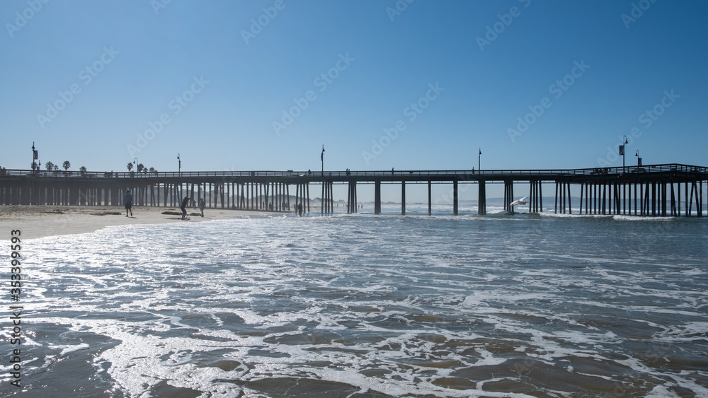 Obraz premium pier, beach, waves, sand and people strolling