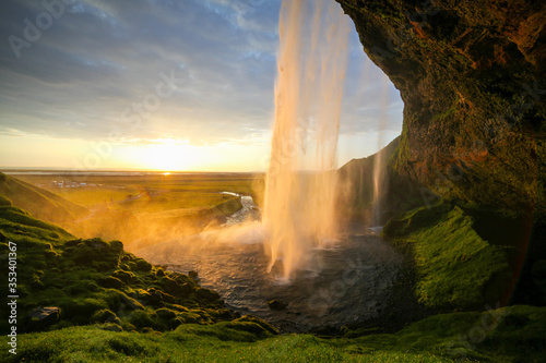 Waterfall Selandjafoss Iceland at sunset or sunrise. Beautiful waterfall in Iceland. Golden hour. Cave and waterfall. Travel in Iceland. Beautiful sky against the big waterfall. inside the water. 