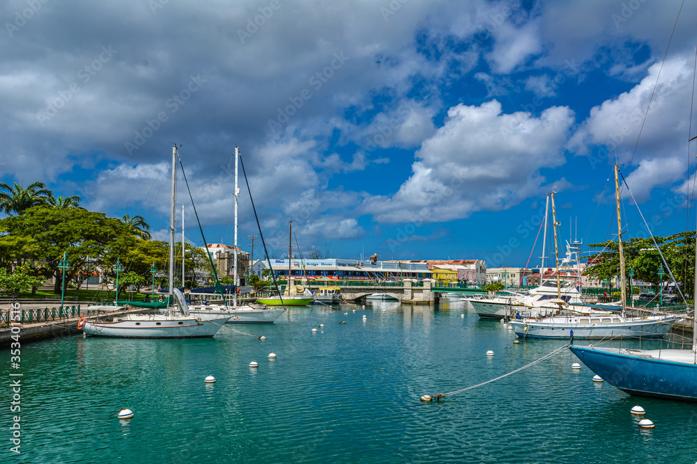 Bridgetown, Barbados - 22 Sept 2018: Sailing yachts moored in the downtown marina bay of Bridgetown, Barbados, Caribbean. White clouds in the blue sky. Copy space