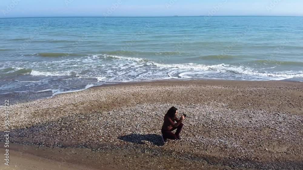 Beautiful aerial view of a drone, a woman with a camera stands on the beach and photographs the ocean.
Beautiful aerial view of a drone, a woman with a camera stands on the beach and photographs the ocean.
