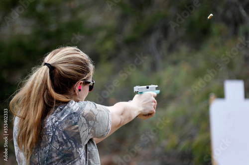Woman shooting a pistol as empty case is ejected.