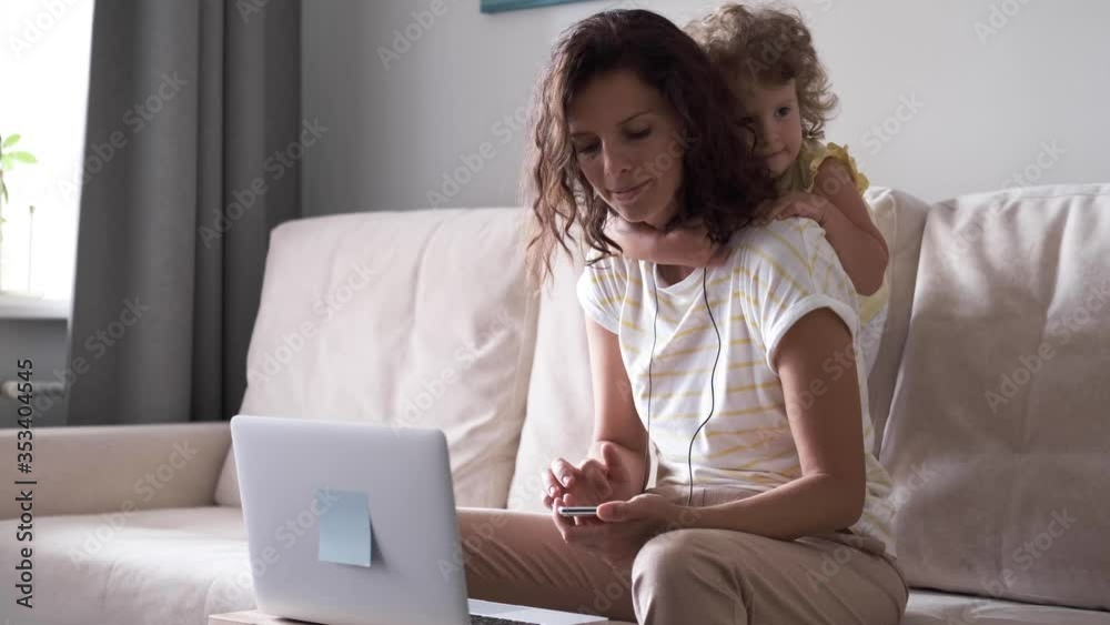 Mother multitasking using laptop computer at home with her baby. Candide genuine and real life mom works and parenting. Self-isolation. Mother multitasking using laptop computer at home with her baby. Candide genuine and real life mom works and parenting. Self-isolation.