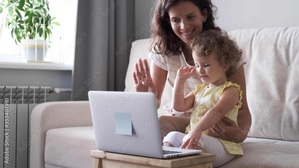 Happy family mom and cute little baby daughter laugh use laptop for video call. Self isolation concept Happy family mom and cute little baby daughter laugh use laptop for video call. Self isolation concept