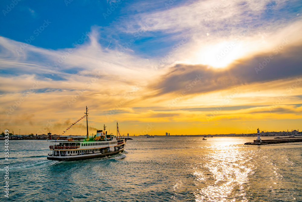 Famous ferries, VAPUR, in Istanbul is taking off from kadikoy port during sunset with colorful sky background. Panoramic view of the Bosporus 