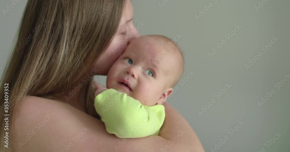 Perplexed, sleepy baby looks around and gets a kiss on mother's hands Perplexed, sleepy baby looks around and gets a kiss on mother's hands