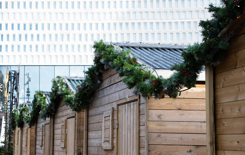 Christmas market wooden stalls with Christmas wreath running along the edges of the roof Christmas market wooden stalls with Christmas wreath running along the edges of the roof