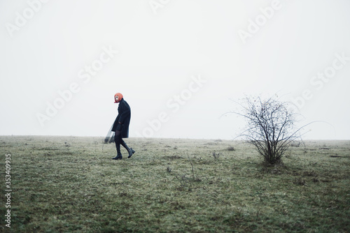 Fashion girl with red bob haircut and black clothes in dramatic cold foggy autumn field