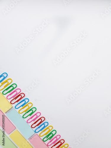 Multicolored metal paper clips on a white background.
