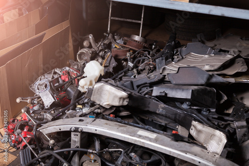 A pile of spare parts at a car service warehouse with different units of auto iron-plastic on the lower rack at an auto-parsing or garage.
