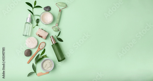 Spa treatment concept, flat lay composition with natural skin care products. cosmetic bottle containers with green leaves on light green background top view.space for text