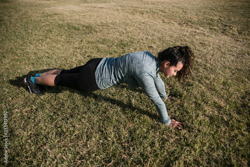 Woman doing push ups on the grass.