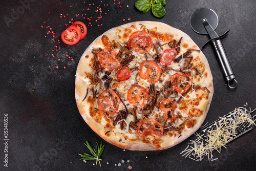 Fresh hot pizza with meat, mushrooms, cheese and tomatoes made in an oven