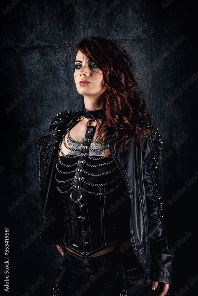 Young woman with scarified face, wearing a studded leather jacket