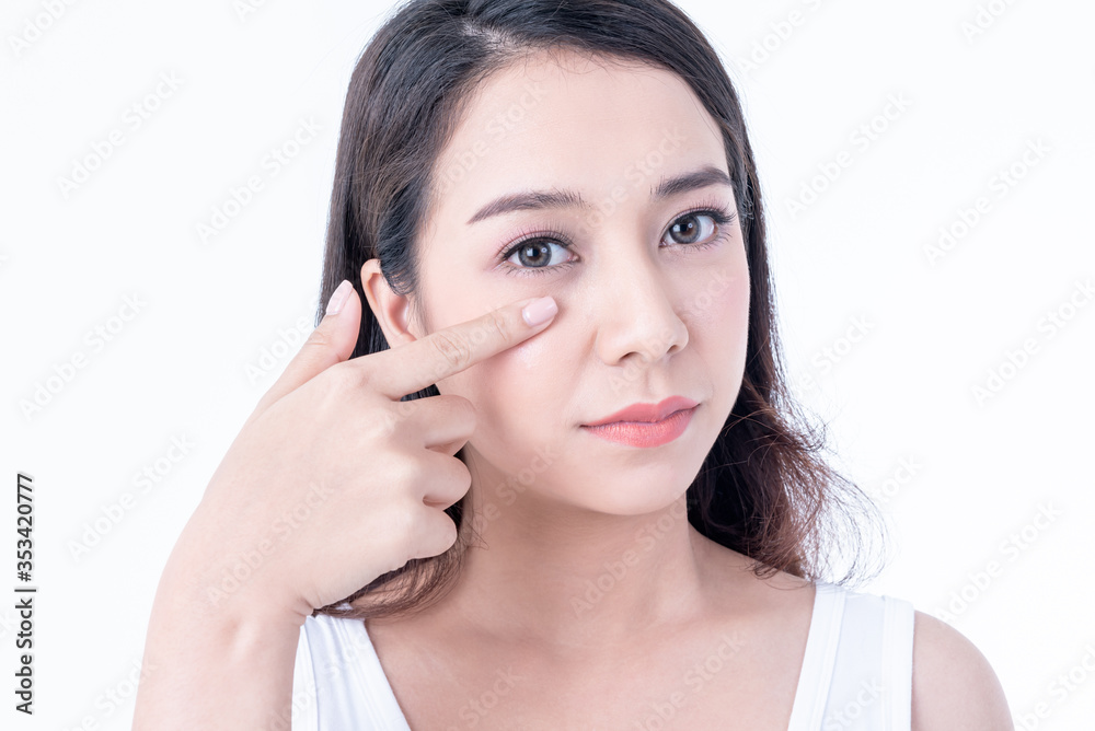 Portrait images of Asian young, pretty woman is 25 years old, She is using finger to touch the skin under the eyes, On white background, to people and beauty concept Portrait images of Asian young, pretty woman is 25 years old, She is using finger to touch the skin under the eyes, On white background, to people and beauty concept
