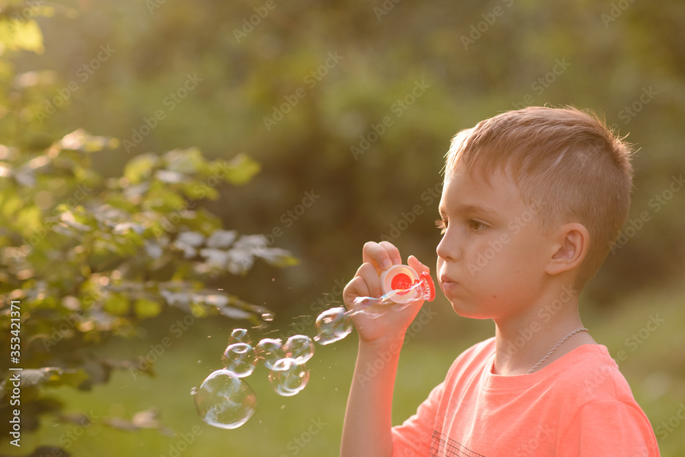 Portrait of a young boy blowing soap bubbles in a park. Close up. Portrait of a young boy blowing soap bubbles in a park. Close up.