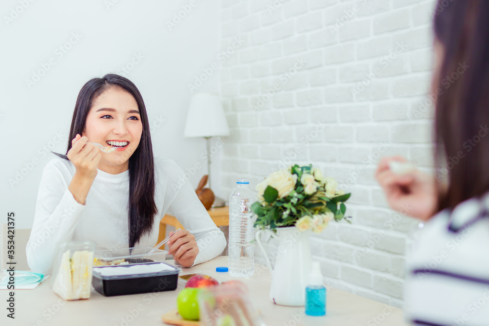 Two beautiful Asian women are sitting and eating new normal lifestyle couple friend use plastic spoon and fork eat food Two beautiful Asian women are sitting and eating new normal lifestyle couple friend use plastic spoon and fork eat food