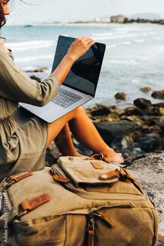 Young pretty female freelancer working on a laptop, remote work concept. Work by the sea. Using modern technology, the Internet