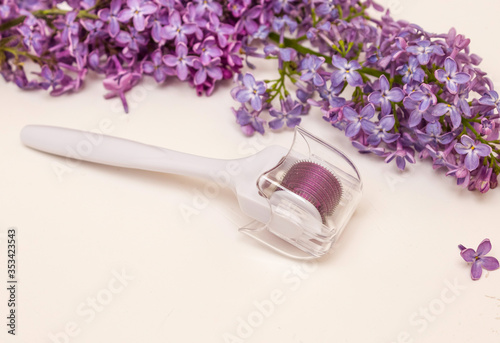 Mesoroller and lilac flowers on a white background. Concept of skin care, anti-wrinkle, Spa.