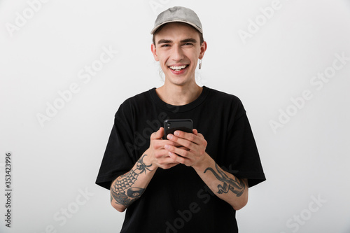 Fotografi Portrait of happy young man wearing black clothes using cellphone and smiling