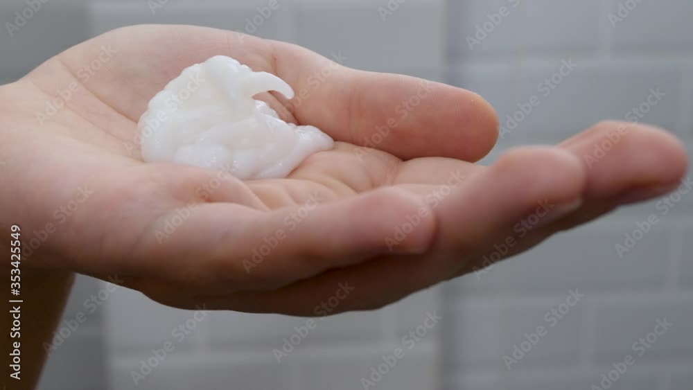 Unrecognizable person woman pour hair conditioner in hands. Cosmetic liquid squeeze in hand in home bathroom on ceramic tiles background. Pour body care lotion Unrecognizable person woman pour hair conditioner in hands. Cosmetic liquid squeeze in hand in home bathroom on ceramic tiles background. Pour body care lotion