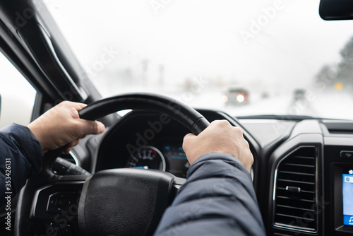 Man's hands on a steering wheel of SUV in winter