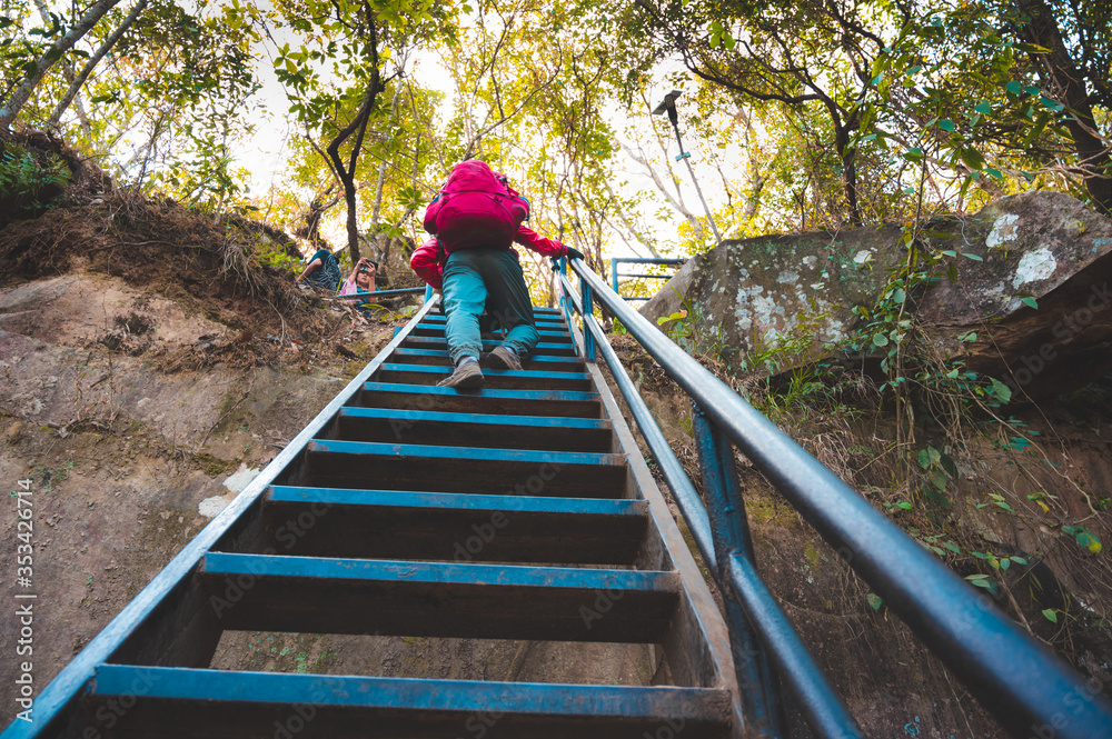 Travelers carrying a heavy red backpack to travel to Phu Kradueng Thailand. On the way, walk up the stairs. Travelers carrying a heavy red backpack to travel to Phu Kradueng Thailand. On the way, walk up the stairs.