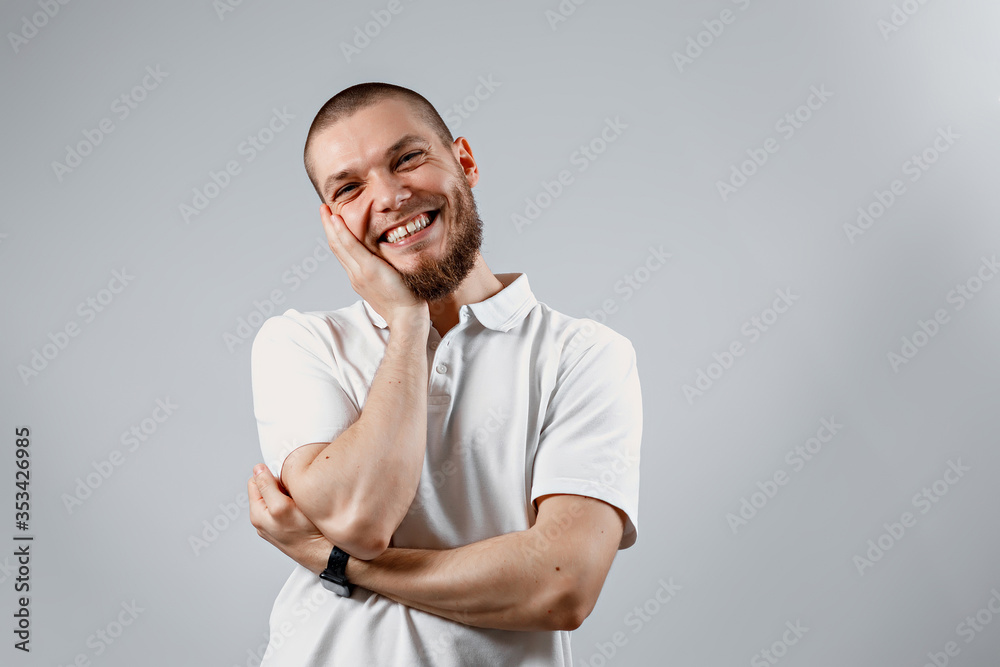 Portrait of a handsome young shy man in a white T-shirt on a gray background. isolated, Copyspace Portrait of a handsome young shy man in a white T-shirt on a gray background. isolated, Copyspace