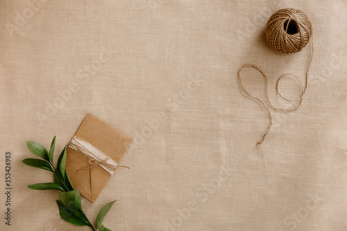 Top view image fashion designer background concept.Flat lay sewing scrapbooking accessory. Skein of twine, vintage envelope on brown linen fabric at home studio. Space for design mockup